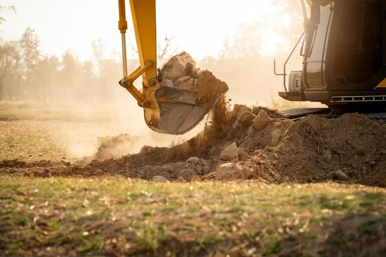 Backhoe working by digging soil at construction site. Bucket teeth of backhoe digging soil. Crawler excavator digging on soil. Excavating machine. Earth moving machine. Excavation vehicle.